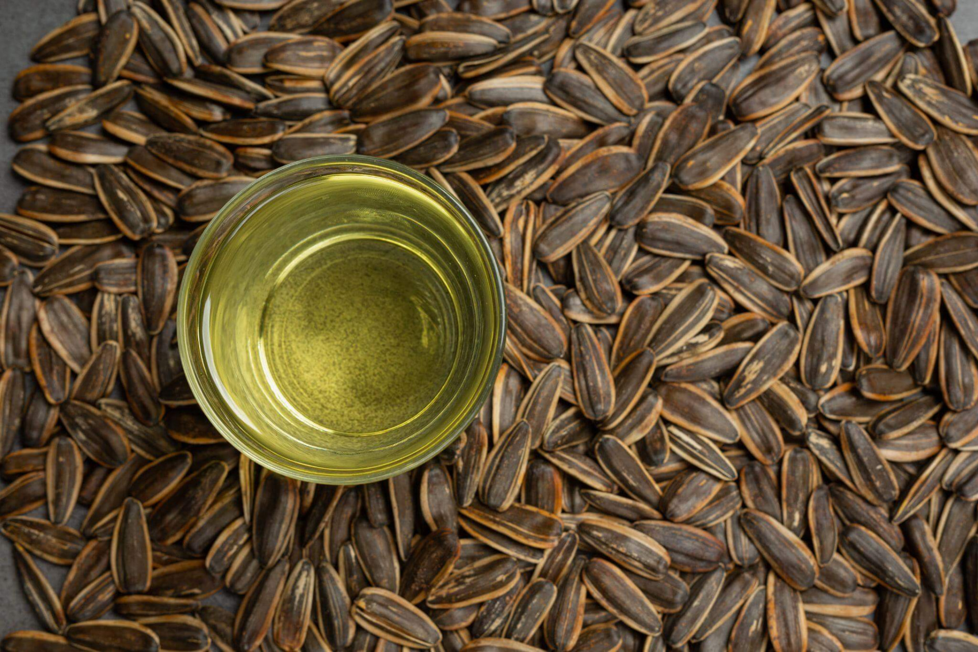 Sunflower oil in a bottle on a table beside sunflower seeds